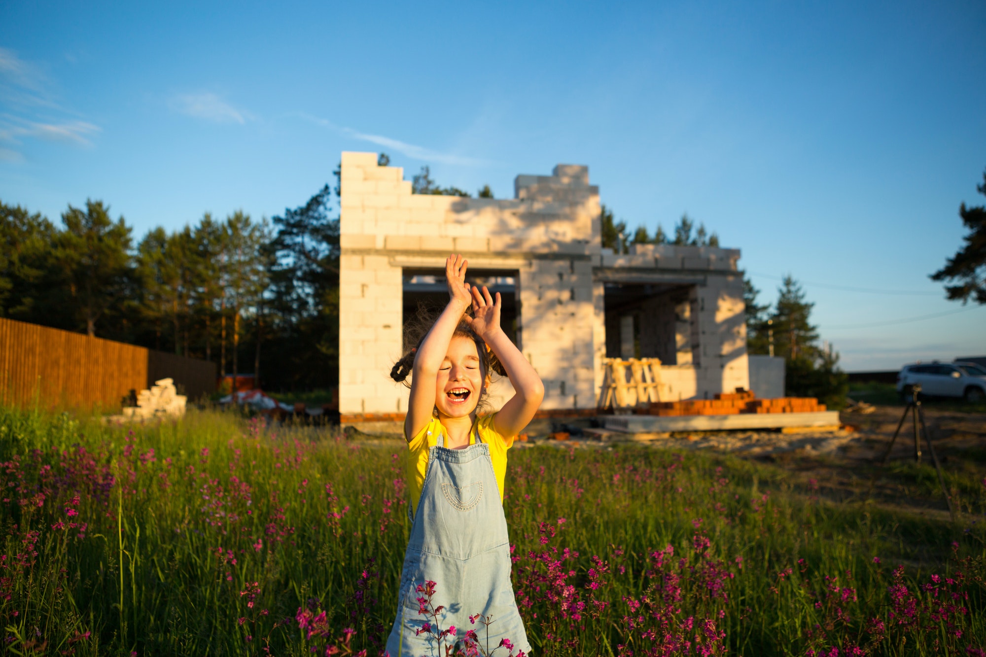 A little girl plays and dances near the construction site of her future house